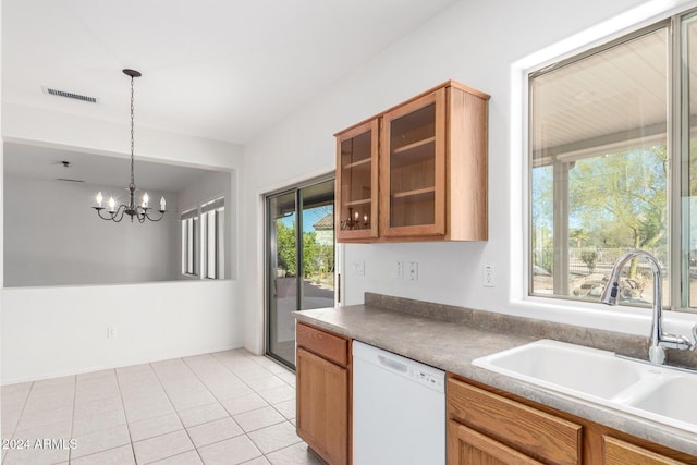 kitchen with white dishwasher, sink, pendant lighting, light tile patterned floors, and an inviting chandelier