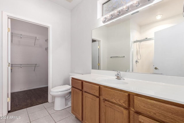 bathroom featuring tile patterned floors, toilet, vanity, and walk in shower