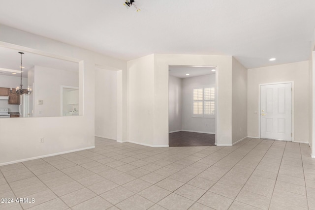 unfurnished room featuring a notable chandelier and light tile patterned floors