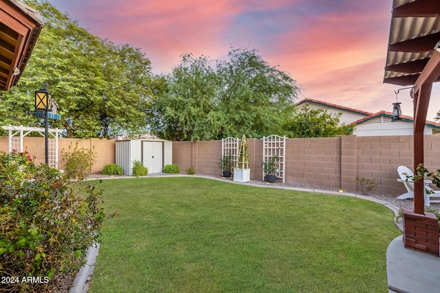 yard at dusk featuring a storage unit