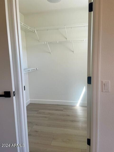 walk in closet with light hardwood / wood-style floors