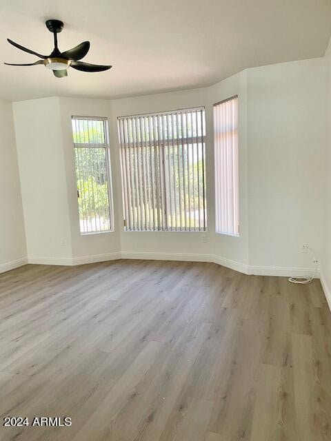 spare room with ceiling fan and light wood-type flooring