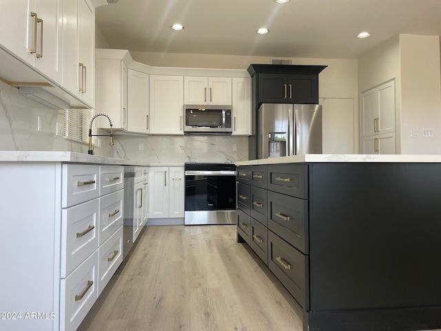 kitchen with sink, light hardwood / wood-style floors, decorative backsplash, white cabinets, and appliances with stainless steel finishes