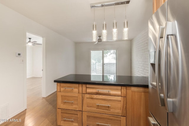 kitchen with hanging light fixtures, stainless steel refrigerator with ice dispenser, ceiling fan, and light hardwood / wood-style flooring