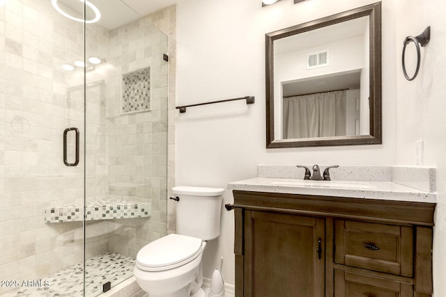 bathroom with vanity, a shower with door, and toilet