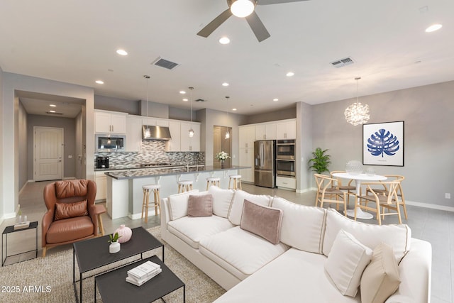 living room featuring ceiling fan with notable chandelier