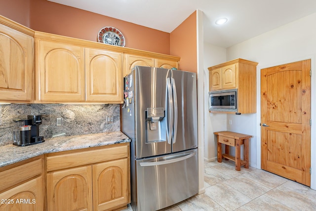 kitchen featuring appliances with stainless steel finishes, light brown cabinetry, backsplash, and light stone countertops