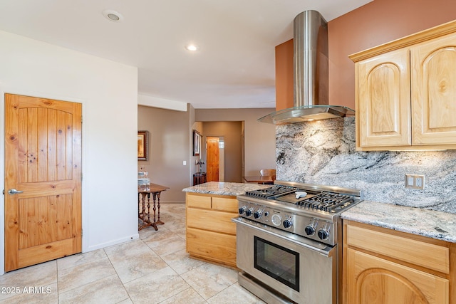 kitchen featuring wall chimney exhaust hood, tasteful backsplash, light brown cabinetry, stainless steel stove, and light stone counters