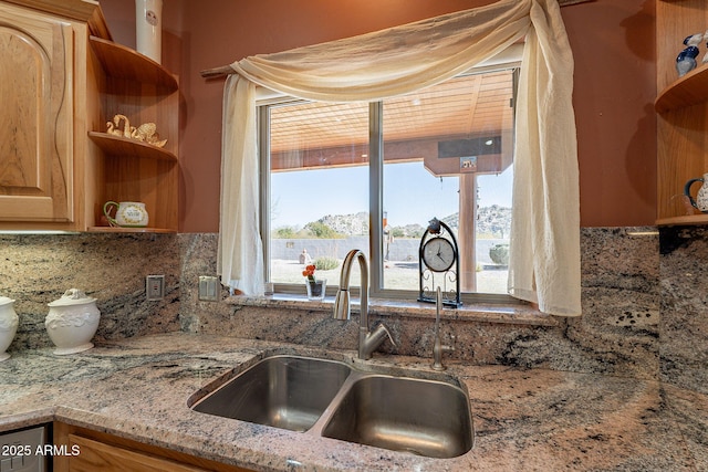 kitchen with decorative backsplash, sink, and light stone counters