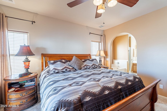 bedroom with ceiling fan, multiple windows, and ensuite bath