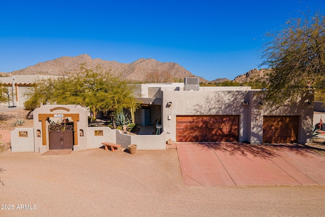 adobe home featuring a mountain view, central AC unit, and a garage