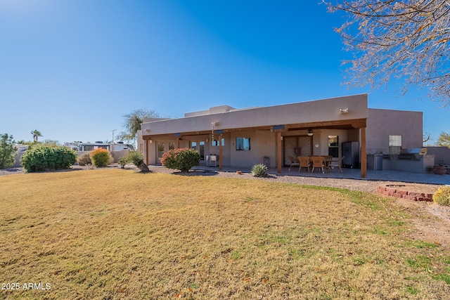 rear view of property featuring exterior kitchen, a patio area, a yard, and ceiling fan