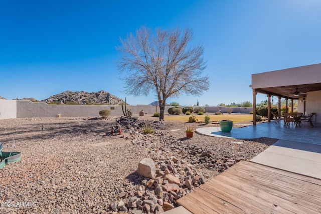 view of yard featuring ceiling fan, a patio area, and a mountain view