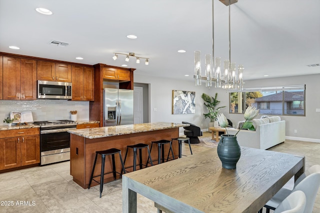 kitchen with hanging light fixtures, a kitchen breakfast bar, a center island, and appliances with stainless steel finishes