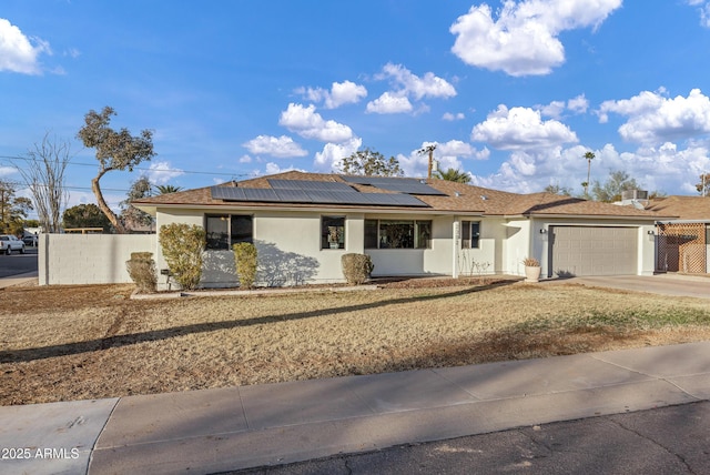 ranch-style home with a garage and solar panels