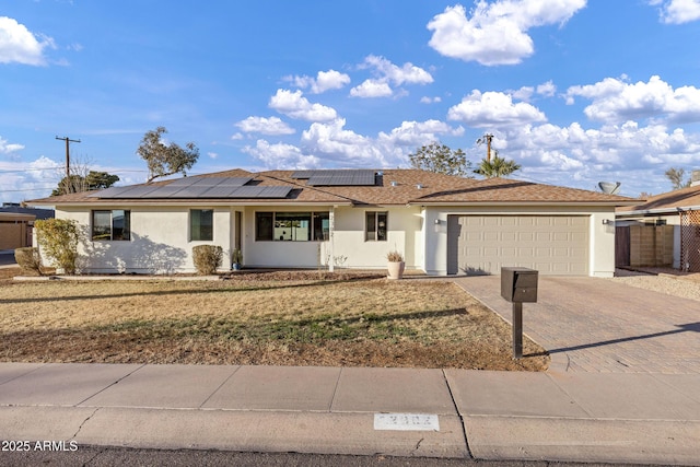 single story home featuring a garage, a front yard, and solar panels