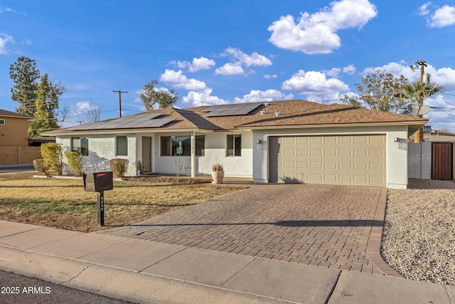 ranch-style house featuring a garage and solar panels