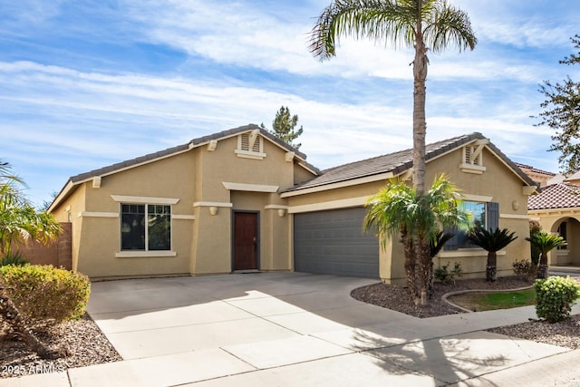 view of front of home with concrete driveway, a tile roof, an attached garage, and stucco siding