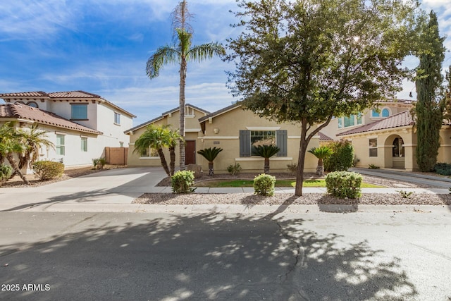 mediterranean / spanish home with concrete driveway, a residential view, and stucco siding