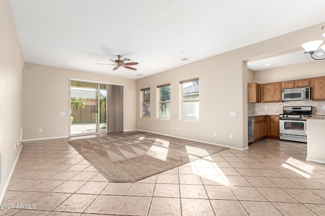 interior space featuring a healthy amount of sunlight, brown cabinetry, stainless steel appliances, and open floor plan