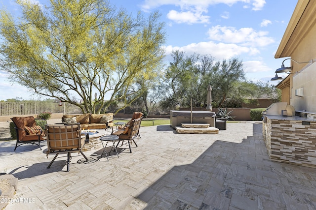 fenced backyard with a hot tub, an outdoor hangout area, exterior kitchen, and a patio