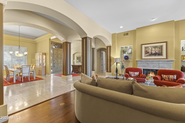 living room featuring a tiled fireplace, arched walkways, a chandelier, dark wood-type flooring, and recessed lighting