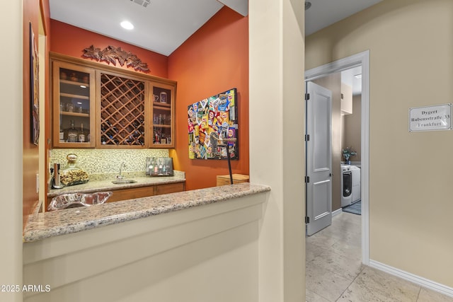 indoor wet bar featuring baseboards and backsplash