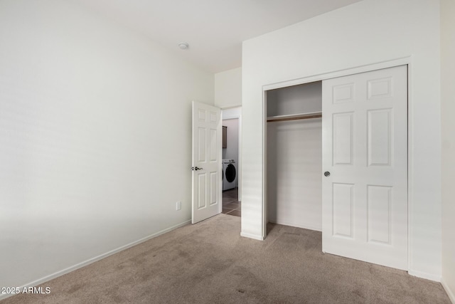 unfurnished bedroom with a closet, washer / clothes dryer, and light carpet