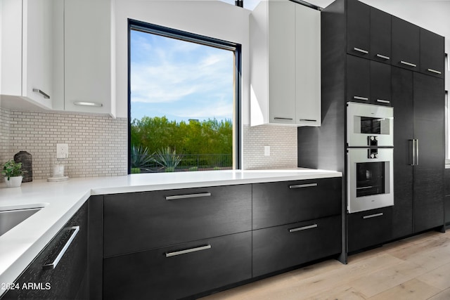 kitchen featuring light hardwood / wood-style floors, decorative backsplash, a healthy amount of sunlight, and white cabinetry