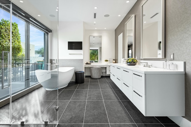 bathroom featuring tile patterned flooring, plenty of natural light, a bathtub, and vanity