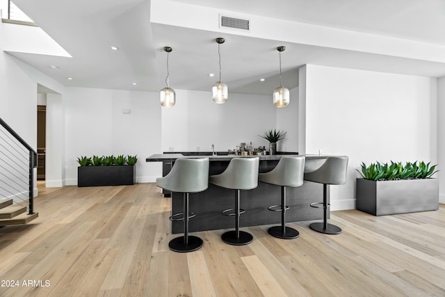 kitchen featuring a kitchen breakfast bar, light hardwood / wood-style floors, and hanging light fixtures