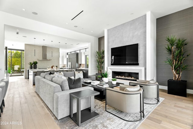 living room featuring light wood-type flooring and a large fireplace