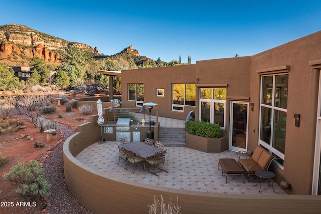 view of patio featuring outdoor dining area, a mountain view, and grilling area