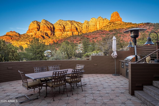 view of patio with a mountain view, outdoor dining area, and area for grilling