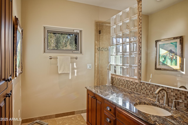 full bath with a tile shower, backsplash, baseboards, and vanity