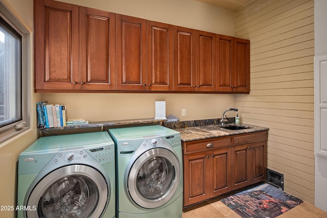 washroom with cabinet space, a sink, and separate washer and dryer