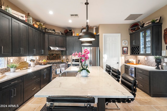 kitchen featuring stainless steel appliances, wine cooler, pendant lighting, a kitchen island with sink, and a breakfast bar