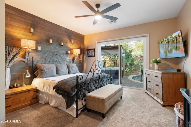 carpeted bedroom featuring access to outside, wood walls, and ceiling fan