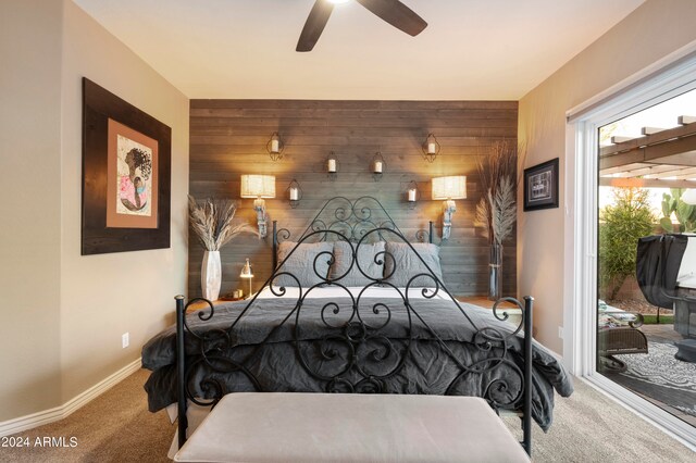 bedroom with access to exterior, carpet, ceiling fan, and wood walls