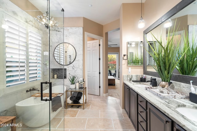 bathroom featuring a chandelier, vanity, plenty of natural light, and a bathing tub