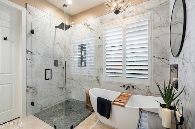 bathroom with tile patterned flooring, shower with separate bathtub, and an inviting chandelier