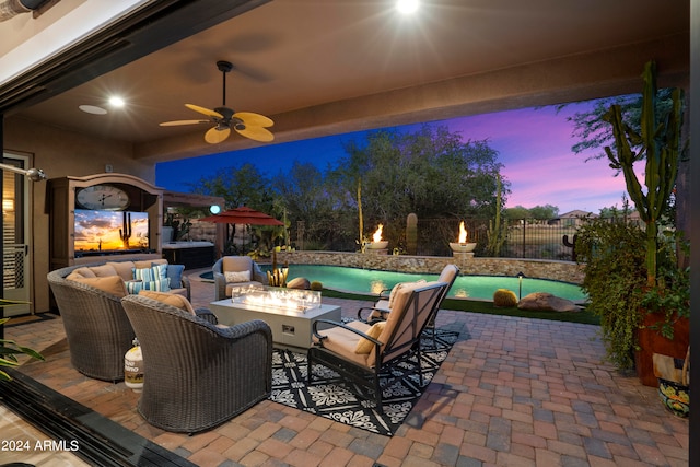 patio terrace at dusk with ceiling fan and an outdoor living space with a fire pit