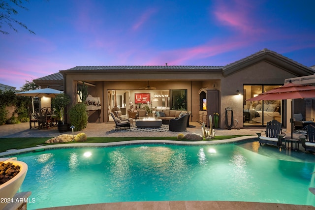 pool at dusk with a patio area, ceiling fan, and an outdoor hangout area