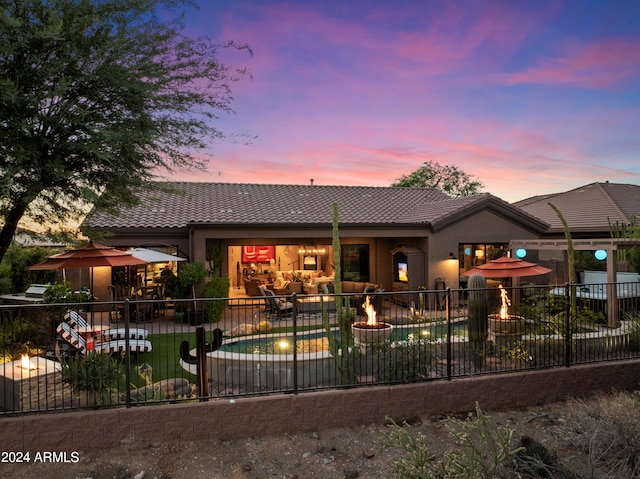 back house at dusk with a patio and a fenced in pool