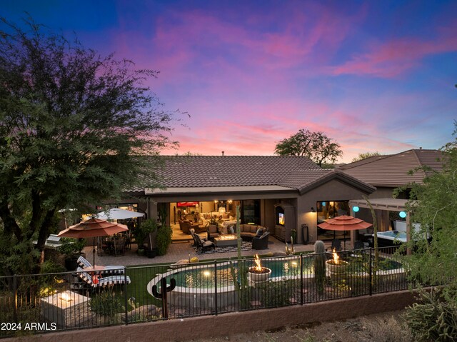 back house at dusk featuring a fenced in pool, an outdoor living space, and a patio