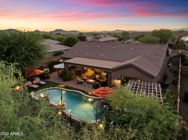 pool at dusk with a mountain view and a patio area