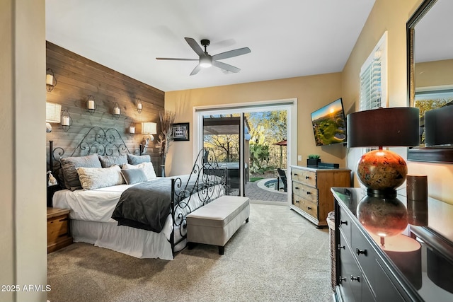 carpeted bedroom featuring ceiling fan, access to exterior, and wooden walls