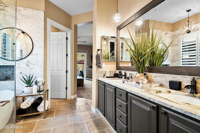 bathroom with a bathing tub, vanity, and a notable chandelier