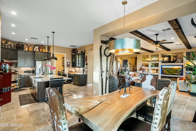 dining area featuring beamed ceiling, ceiling fan, and sink