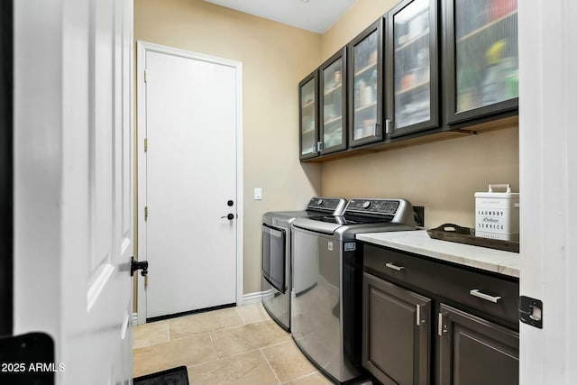 laundry area featuring cabinets, light tile patterned floors, and separate washer and dryer